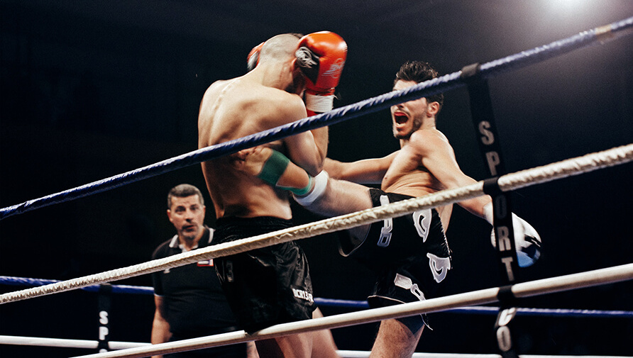 MMA-gevecht waarbij een man een andere man in zijn zij trapt